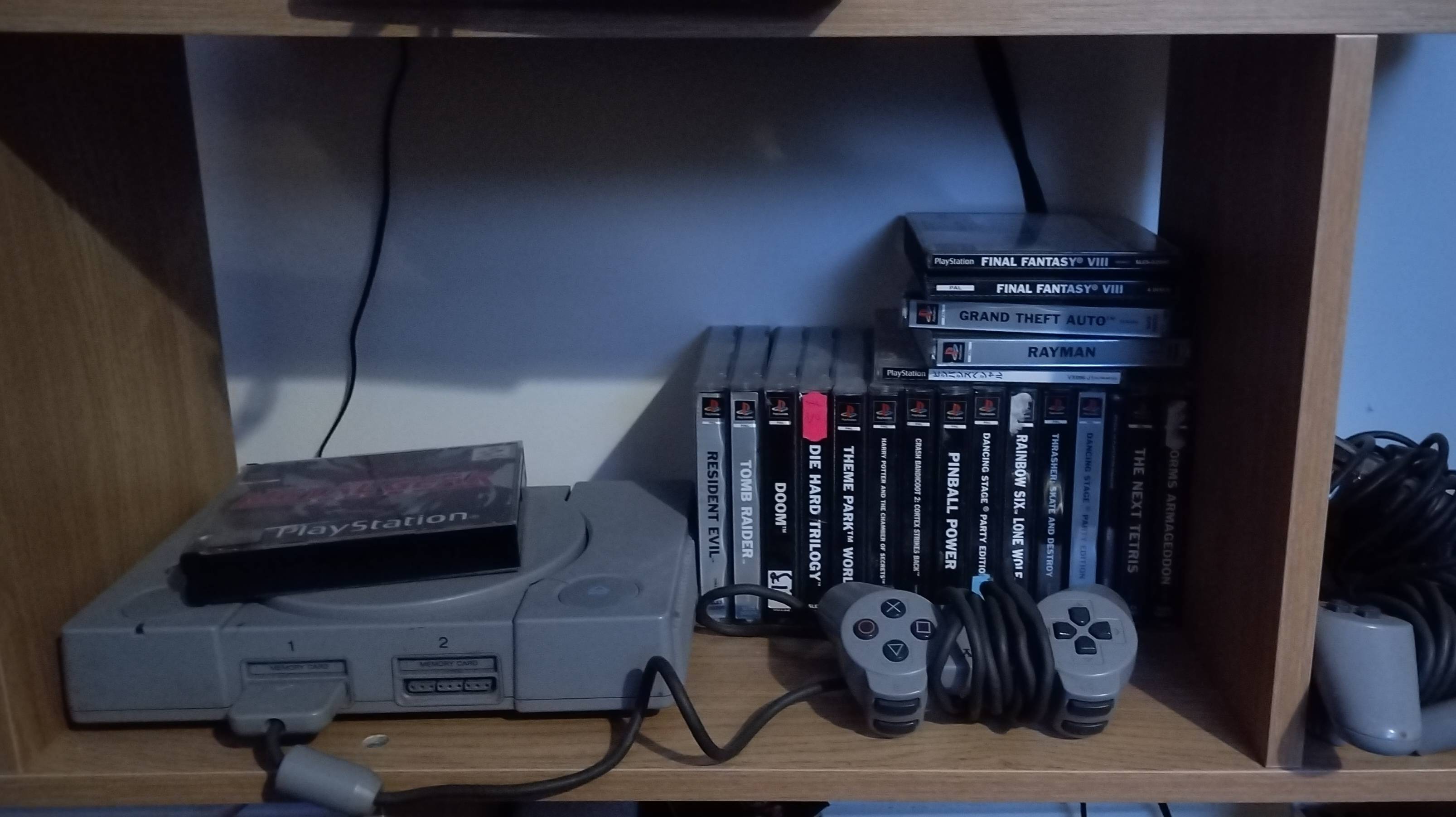 A Playstation One With Controlers And Games Including Tomb Raider GTA And Resident Evil